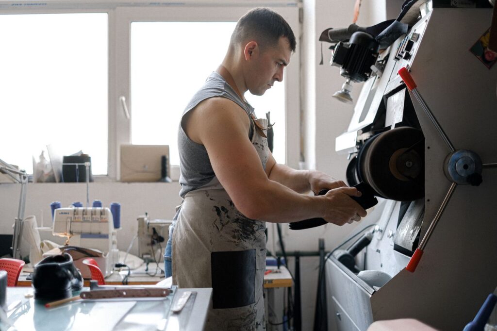 A man skillfully operates industrial machinery in a workshop, focusing on detailed craftsmanship.